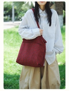 Close-up of red and black houndstooth canvas tote bag shown in an outdoor lifestyle setting