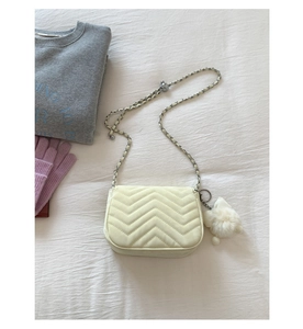 Detail der cremeweißen Stepptasche mit V-Nahtmuster und silbernem Ketten-Schultergurt