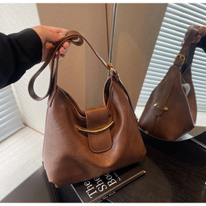 Close-up of brown leather hobo bag with elegant gold metal buckle in soft natural light
