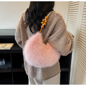 Detailed close-up of a pink fuzzy crescent bag with beaded orange and white strap