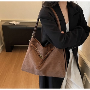Detail of dark brown suede tote bag featuring a vintage gold horsebit buckle and texture