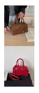 Detail of suede boston bag showing leather handles and metal heart pendant accessory