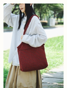 Close-up of red and black houndstooth pattern tote bag in an outdoor setting