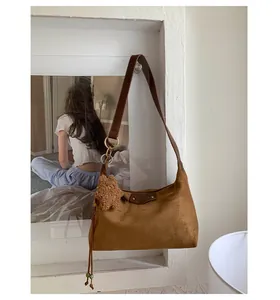 Détail d'un sac hobo en daim marron avec pendentif ours et logo métallique