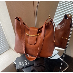 Detail of vintage brown tote with magnetic flap and elegant golden crescent metal hardware