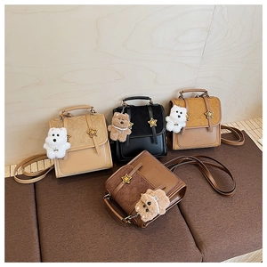 Close-up of leather bags with star buckles and plush puppy charms on wooden display
