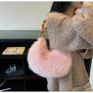 Detail of pink faux fur crescent bag with orange bead handle shown on model shoulder