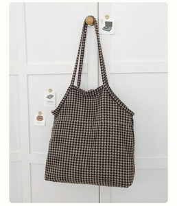 Detail of classic black and white houndstooth knit tote bag texture on a wooden hook