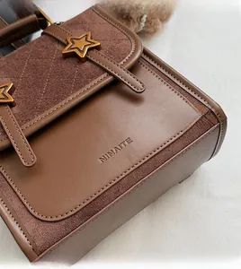 Close-up of leather texture and gold star buckles on a vintage brown messenger bag