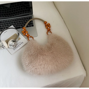 Detail of fuzzy brown crescent bag with wooden bead handle and braided cord on a white desk