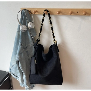 Détail du sac hobo en daim noir avec bandoulière chaîne dorée et mini pochette