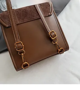 Detail of dark brown leather backpack featuring diamond quilted suede flap and gold hardware