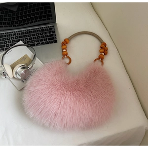 Detail of pink faux fur handbag with stylish wooden bead handle on a white desk