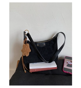 Détail du sac hobo en daim noir avec rivet doré et breloque ours en peluche marron