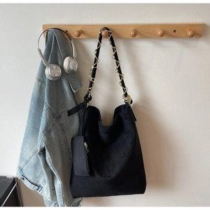 Détail du sac hobo en daim noir avec bandoulière tressée et petite pochette zippée