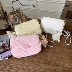Drei gesteppte Kettentaschen in Rosa, Beige und Weiß mit flauschigen Anhängern im Detail
