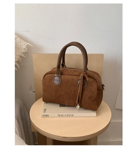 Detailed view of caramel suede Boston bag with leather handles and silver ball charm