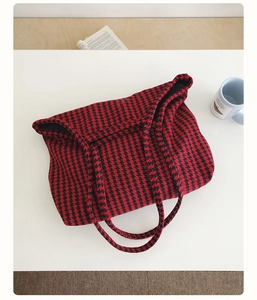Detail shot of a red and black houndstooth knit tote bag with durable shoulder straps