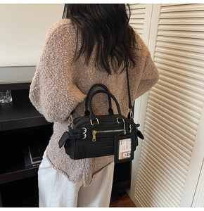 Detail of black underarm bag with gold hardware and transparent card holder on shoulder
