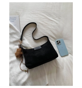Détail d'un sac hobo en daim noir avec pendentif étoile en peluche et plaque logo