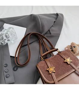 Close-up of brown textured shoulder bag with gold star buckles on grey blazer background