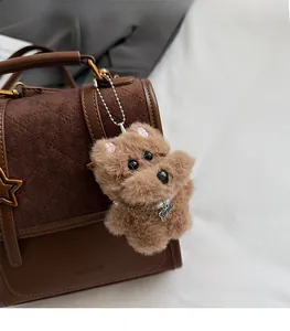 Brown plush dog keychain with Top Dog tag and pearl collar detail on a stylish bag