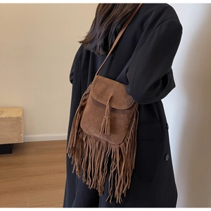 Gros plan d'un sac bandoulière en daim marron avec franges et détails tressés sur modèle