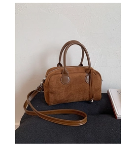Close-up of brown suede pillow bag with smooth leather handles and metal zipper detail