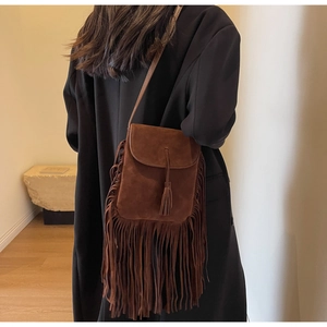 Vue détaillée d'un sac bandoulière marron en daim à franges style bohème porté par un mannequin
