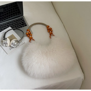 Detail of white faux fur handbag with unique wooden bead handle and woven strap design