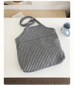 Close-up of houndstooth tote bag on white desk with casual lifestyle accessories