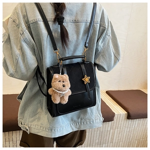 Detail of black quilted backpack with gold star buckle and cute plush bear charm