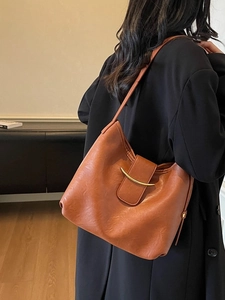 Retro caramel textured leather shoulder bag with gold crescent buckle on a model