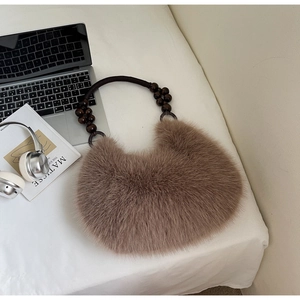 Detail of faux fur hobo bag with unique dark wooden beaded handle on white fabric