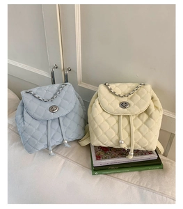 Dettaglio di zaini trapuntati in azzurro e crema con coulisse di perle e manici a catena