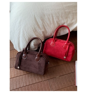 Detail of red and brown suede Boston bags featuring heart tassels and curved handles