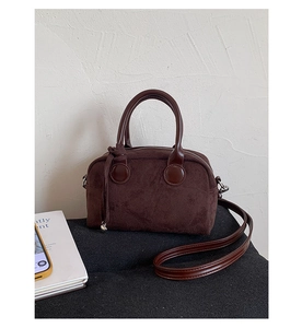 Detail of dark brown faux suede handbag showing smooth leather trim and metal zipper