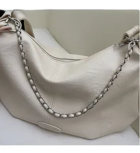 Gros plan du sac à bandoulière beige avec bandoulière en chaîne et étiquette en cuir