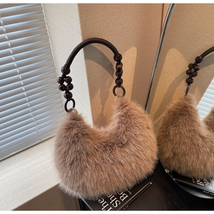 Detail of khaki faux fur bag featuring chunky wooden bead handle and metal ring accents