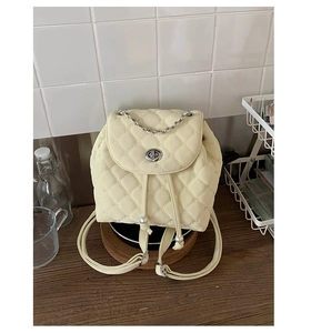 Dettaglio del mini zaino trapuntato crema con coulisse di perle e manico a catena