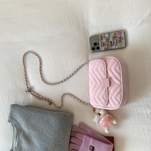 Detailansicht der rosa gesteppten Kettentasche mit Monster-Anhänger und Accessoires