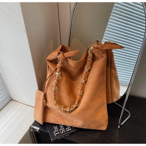 Détail d'un sac cabas en daim caramel avec bandoulière chaîne et pochette assortie