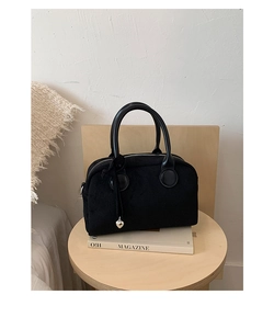 Detail of black suede Boston bag with silver heart charm on a wooden stool