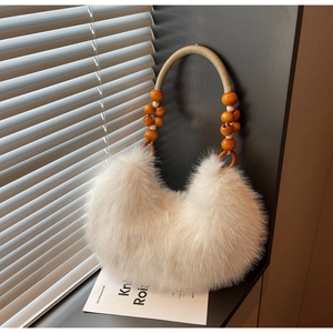Detail of white faux fur crescent bag with woven rope handle and orange wooden beads