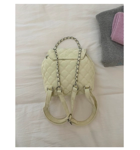 Dettaglio dello zaino beige trapuntato con motivo a rombi e manico a catena in metallo