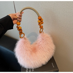 Detailed shot of pink fuzzy crescent bag with orange wooden beads on a woven handle