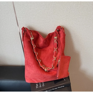 Détail du sac fourre-tout en daim rouge avec chaîne dorée et petite pochette zippée