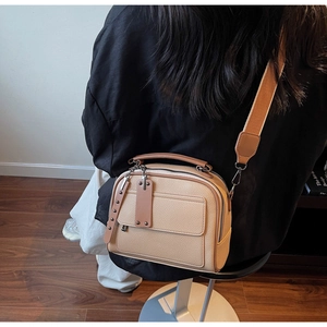 Detail of beige litchi grain crossbody bag with wide fabric strap on a model back view