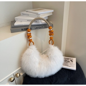 Detail of white faux fur crescent bag featuring woven handle with large amber wood beads