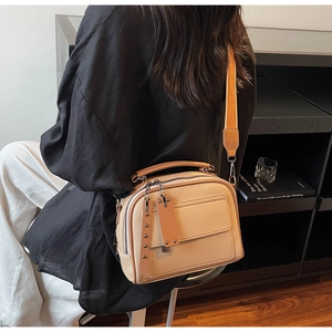 Detail of beige crossbody bag featuring lychee texture leather and wide fabric strap
